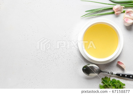 Chicken broth with parsley in bowl on white table. Chicken broth with parsley in bowl on white table. 67158877