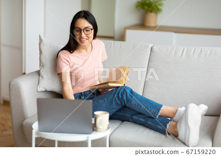Girl Studying Using Laptop And Reading Sitting On Couch Indoor 67159220