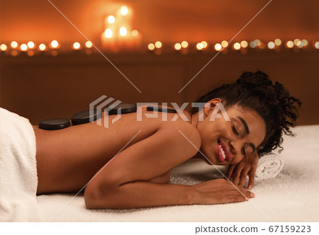 Relaxed african girl enjoying hot stones massage at spa 67159223