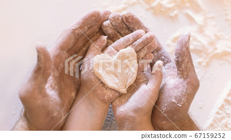 Father And Daughter Holding Heart-Shaped Dough On Hands Indoor, Closeup Father And Daughter Holding Heart-Shaped Dough On Hands Indoor, Closeup 67159252