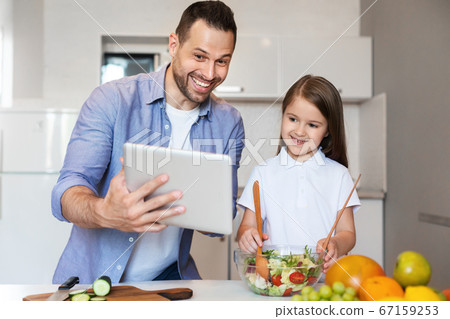 Father And Daughter Using Tablet Cooking In Kitchen At Home Father And Daughter Using Tablet Cooking In Kitchen At Home 67159253