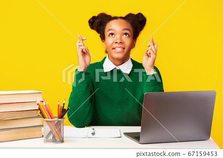 Cheerful black girl crossing fingers using laptop 67159453
