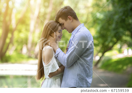 Happy young couple embracing on romantic date at park 67159539