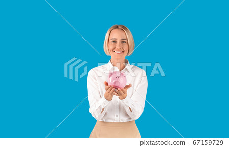 Money savings. Portrait of mature businesswoman holding piggybank on blue background 67159729