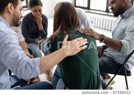 During group therapy session members supporting crying desperate girl 67160032