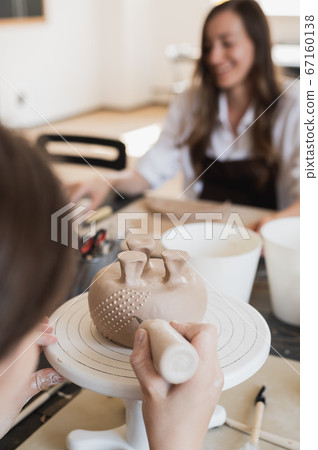 Woman decorating handmade pottery vase close-up 67160138