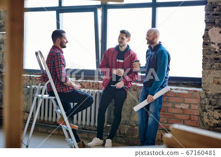 Group of young architects or house designers having coffee and discussing ideas Group of young architects or house designers having coffee and discussing ideas 67160481
