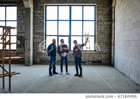 Young foreman or contractor pointing at brick wall of unfinished building Young foreman or contractor pointing at brick wall of unfinished building 67160498