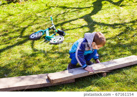 Little boy constructing a wooden road at the backyard Little boy constructing a wooden road at the backyard 67161154