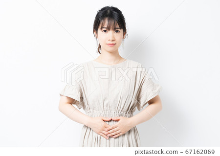Young woman putting her hand on her stomach 67162069
