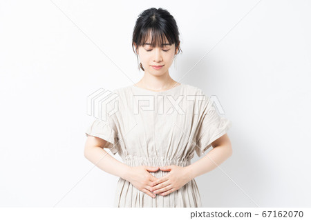 Young woman putting her hand on her stomach Young woman putting her hand on her stomach 67162070