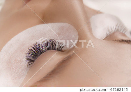 Eyelash Extension Procedure. Close up view of beautiful female eye with long eyelashes, smooth healthy skin. 67162145