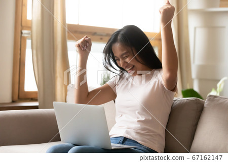 Happy millennial vietnamese lady celebrating online lottery win. 67162147