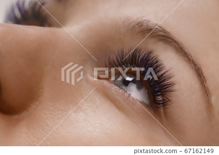 Eyelash Extension Procedure. Close up view of beautiful female eye with long eyelashes, smooth healthy skin. Eyelash Extension Procedure. Close up view of beautiful female eye with long eyelashes, smooth healthy skin. 67162149