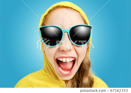 Caucasian joyful girl in a yellow jacket in sunglasses looks at the Caucasian joyful girl in a yellow jacket in sunglasses looks at the 67162353