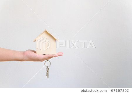Hand holding wooden house and home keychain 67167802