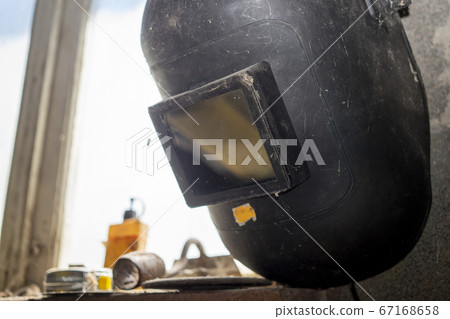 Old metal workers face visor hanging on a wall 67168658