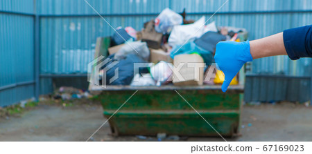 the man in the rubber gloves gave a thumbs-down sign of displeasure. a lot of garbage in a container. garbage collapse. Janitors ' strike. environmental disaster of plastic recycling. and close-up 67169023