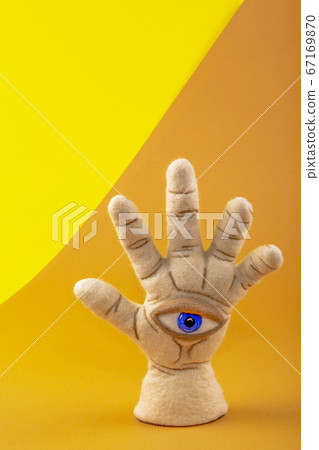 Protective amulet in the shape of an open palm and eye made of felted wool on a colored background Protective amulet in the shape of an open palm and eye made of felted wool on a colored background 67169870
