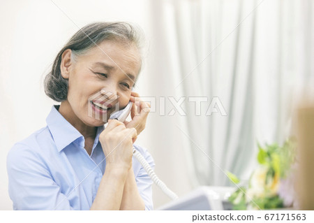 Senior woman talking on landline phone 67171563