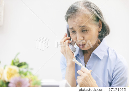 Senior woman talking on landline phone 67171955