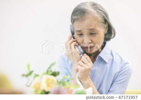 Senior woman talking on landline phone 67171957