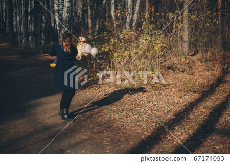 a small child with mother in a warm suit walks in the woods. autumn park. The concept of children's fashion, accessories, outdoor walks a small child with mother in a warm suit walks in the woods. autumn park. The concept of children's fashion, accessories, outdoor walks 67174093