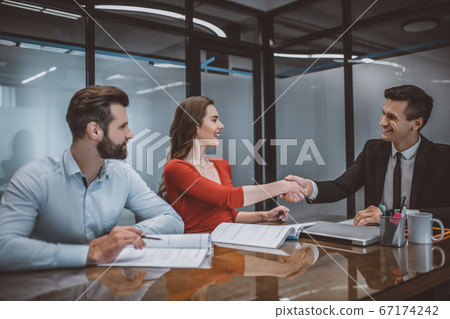 Happy couple making an agreement with a sales agent 67174242