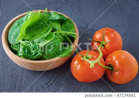 Fresh spinach leaves in wooden bowl and tomato on 67174891