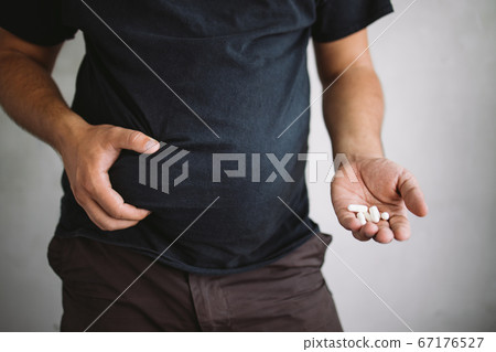 Overweight man holding slimming pills Overweight man holding slimming pills 67176527