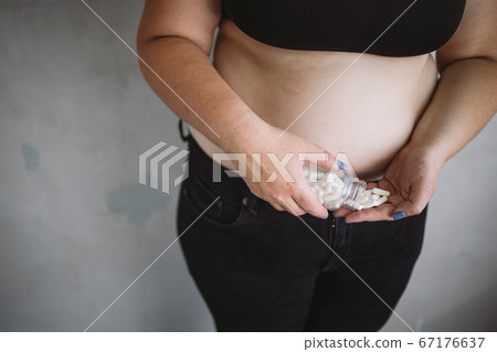 Overweight woman taking dietary pills 67176637