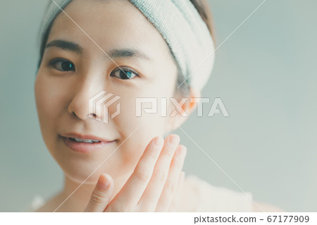 Woman in her 30s with a hair band doing face care 67177909