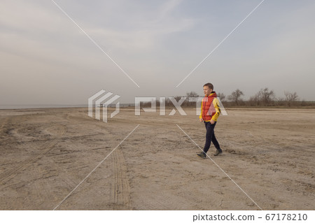 A boy of 10 years old plays soccer on an empty beach. 67178210