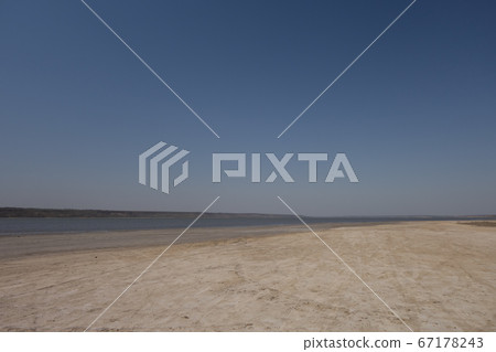 Sandy lake shore on a cloudless windy day. Sandy lake shore on a cloudless windy day. 67178243