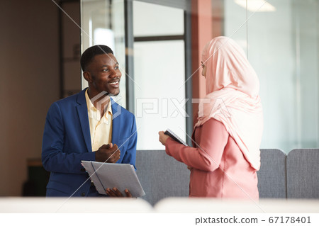 Smiling African Businessman Talking to Muslim Colleague Smiling African Businessman Talking to Muslim Colleague 67178401