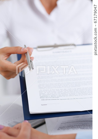 Female arm in white shirt offer contract form on clipboard pad Female arm in white shirt offer contract form on clipboard pad 67179047