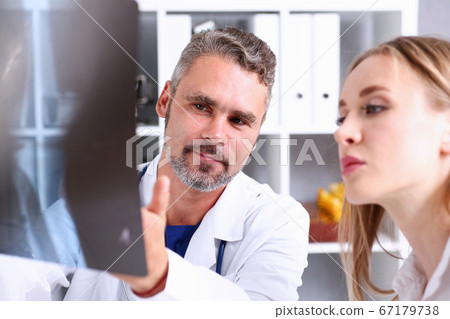 Mature male doctor hold in arm and look at xray photography Mature male doctor hold in arm and look at xray photography 67179738