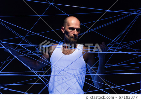 Photo of adult man tangled in threads in neon light Photo of adult man tangled in threads in neon light 67182377
