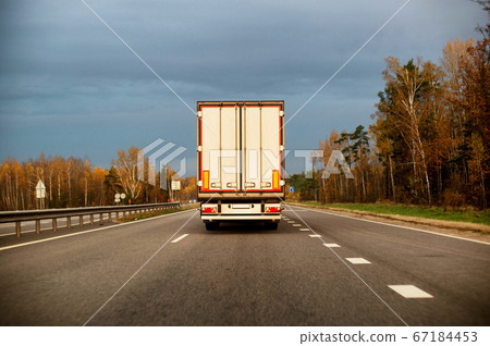 A truck with a refrigerated trailer carries groceries along the highway. The concept of delivery of goods on time, perishable goods, industry 67184453