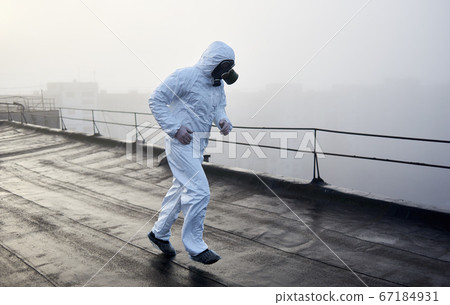 Worker scientist wearing protective coverall and gas mask doing ecological tests on the roof 67184931