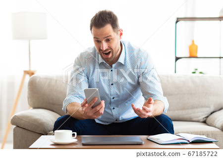 Angry man screaming at mobile phone at home Angry man screaming at mobile phone at home 67185722