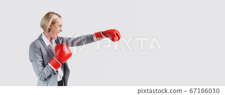 Side view of business lady in boxing gloves throwing punch on light background, panorama with blank space 67186030