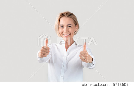 Cheerful business lady showing thumbs up gesture on light background 67186031