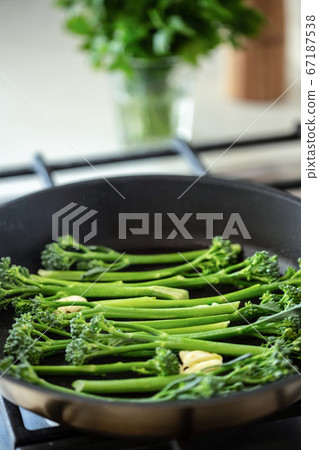 Cooking broccolini in a fried pan. 67187538