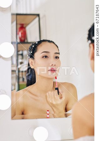 Young woman applying lip gloss Young woman applying lip gloss 67187643