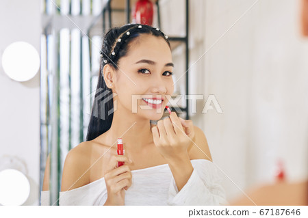 Woman applying liquid lipstick Woman applying liquid lipstick 67187646
