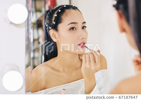 Woman applying lip gloss Woman applying lip gloss 67187647