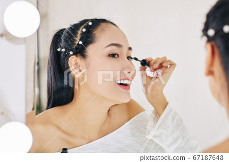 Young woman applying mascara 67187648