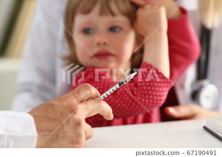 Liitle kid scared looking at the doctor before vaccination Liitle kid scared looking at the doctor before vaccination 67190491