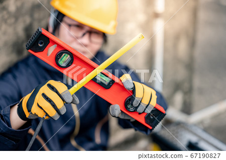 Worker man holding level tool and tape measure 67190827